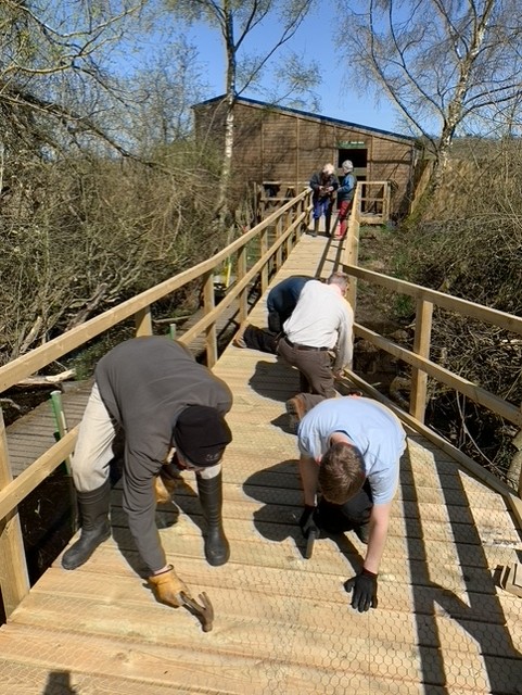 Volunteers on their hands and knees building the new boardwalk